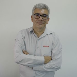 Foto do CEO da Eternit, cujo ticker da ação na B3 é ETER3, Paulo Andrade. Ele é homem, veste uma camisa cinza com o logo da companhia e usa óculos.