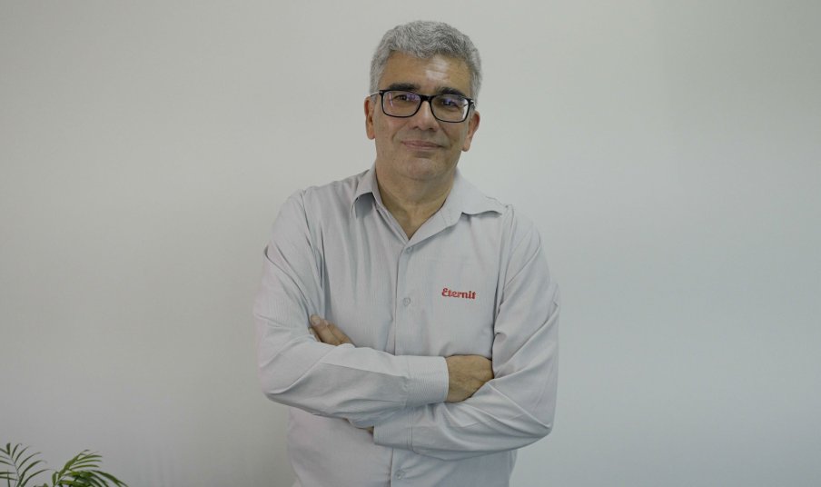 Foto do CEO da Eternit, cujo ticker da ação na B3 é ETER3, Paulo Andrade. Ele é homem, veste uma camisa cinza com o logo da companhia e usa óculos.
