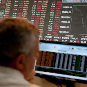 Analista observa painel de ações na bolsa de valores