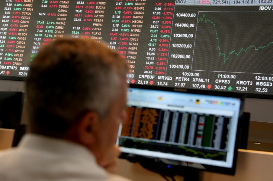 Analista observa painel de ações na bolsa de valores