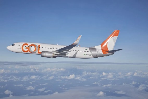 Foto de um avião da Gol com a cauda laranja e o logo da empresa. A matéria descreve a queda das ações da Gol (GOLL4) no Ibovespa.