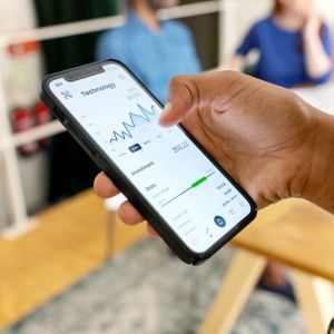 Matéria sobre melhores fiagros de 2023 em que aparece uma mão de uma mulher segurando um celular com gráficos na tela