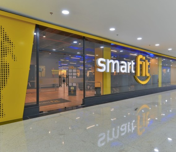 Fachada de uma academia Smart Fit (SMFT3) em vidro, com logo em branco e amarelo