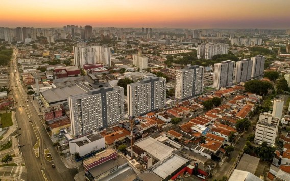 Foto de prédios lançados pela construtora Cury (CURY3). São prédios cinzas sob um céu alaranjado em São Paulo. A matéria fala de receita da Cury em relação ao financiamento imobiliário da Caixa, que sofreu alterações.