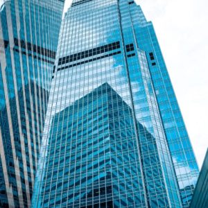 Foto de prédios de vidro com reflexo. A matéria explica quais a tendências do IFIX hoje e para 2025.