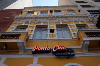 Imagem da fachada do restaurante Ponto Chic, localizado no Largo do Paissandu, em São Paulo. É um prédio antigo, de cores amarelas e brancas.