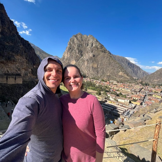 Foto de um casal tirando uma selfie. Eles estão em um sítio arqueológico no Peru.