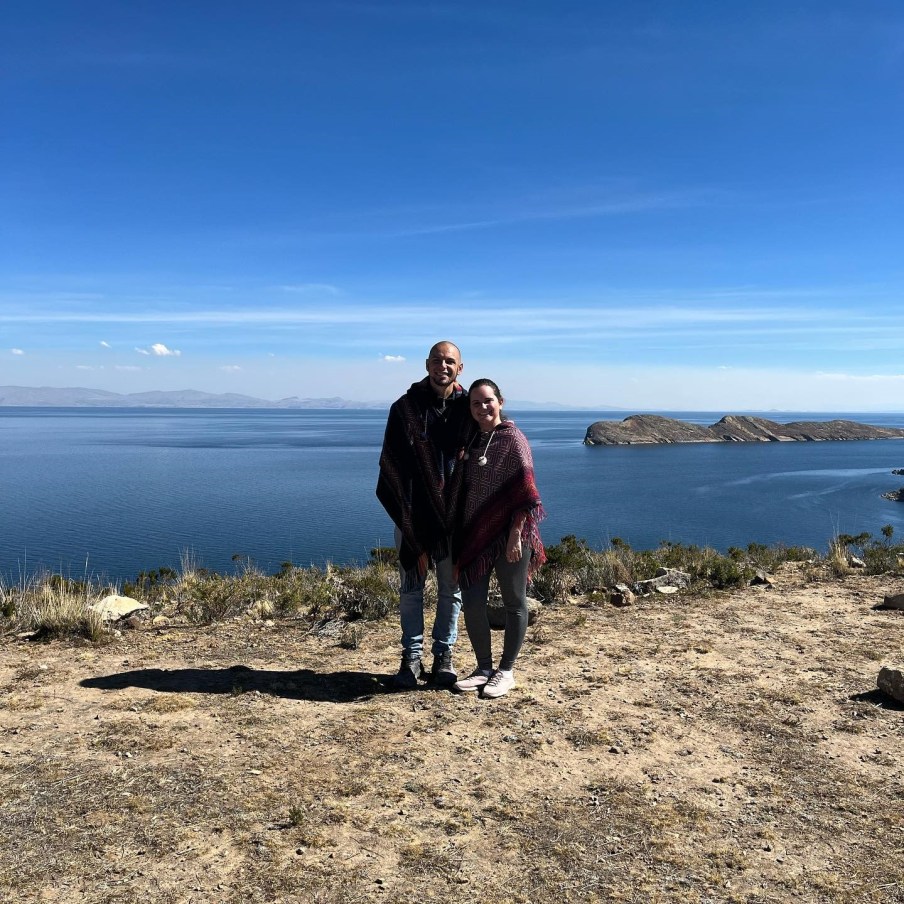 Foto de um casal em frente a um grande lago, na fronteira entre o Peru e Bolivia.
