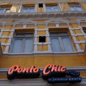 Imagem da fachada do restaurante Ponto Chic, localizado no Largo do Paissandu, em São Paulo. É um prédio antigo, de cores amarelas e brancas.