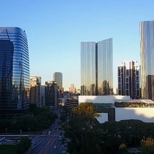 Imagem de uma paisagem com diversos prédios espelhados. Ao fundo, um céu azul.