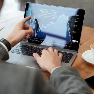 Imagem de um homem analisando um gráfico em um notebook com um café ao lado